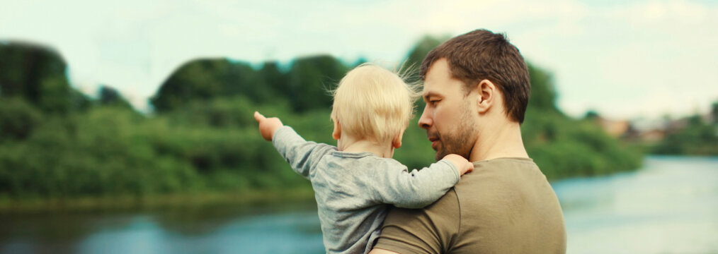 Caucasian father holding his son, dad and child walking together in summer park