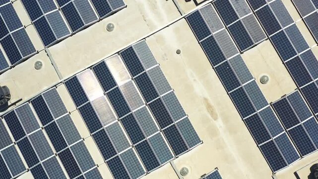 Footage displays solar panels installed on rooftops in a city aerial view. Bright sunlight shines on the panels as they generate energy throughout the day.