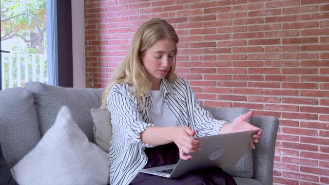 Angry businesswoman getting mad during a remote work online meeting, experiencing a computer glitch, throwing her laptop away in frustration, and staring at the screen with disbelief