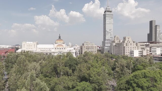 Reveal shot ascending above Alameda Central treetops to unveil Torre Latinoamericana and historic center, Mexico City, shot in D-Log M
