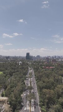 Aerial View of Avenida de los Insurgentes Cutting Through Green Ciudad Universitaria as Drone Flies Backward Toward Mexico City Skyline, Vertical Video, Shot in D-Log M