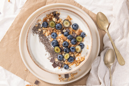 Wholesome yogurt bowl with fresh blueberries, crunchy granola, chia seeds, and chocolate chunks, served in a rustic ceramic dish for a nutritious and delicious morning meal