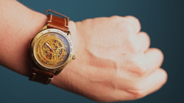 Close-up of a vintage skeleton watch with a brown leather strap on a wrist