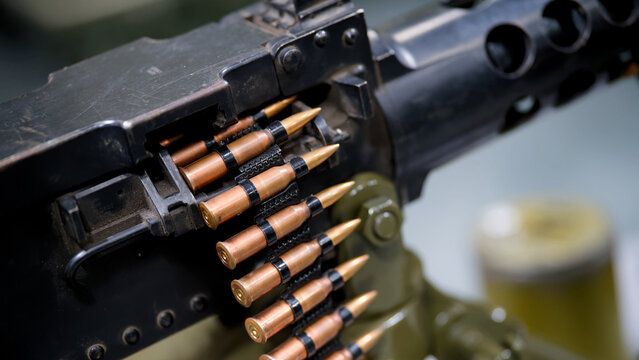 Macro view of copper bullets in an ammunition belt fed into a heavy machine gun used in military aggression and conflict. High resolution photo