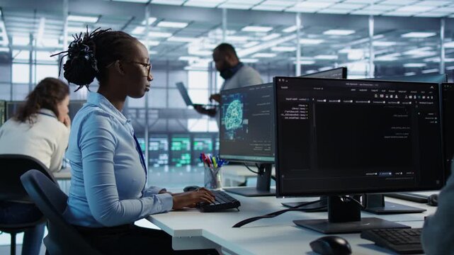 Smiling woman assigned to performing checkup on server room from a secondary camera angle while showing secure storage, threat prevention and cybersecurity monitoring.