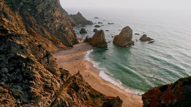 Secluded sandy beach and ocean waves surrounded by steep rocky cliffs