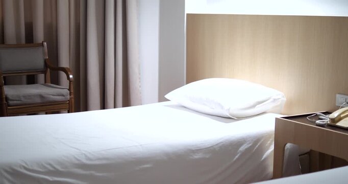Clean white bed with wooden headboard in modern hotel room