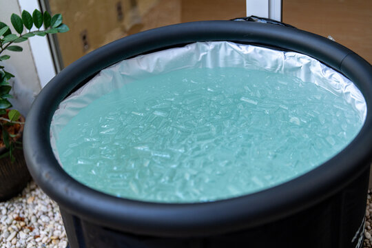 Portable cold plunge tub filled with ice water and ice cubes, prepared for athletic recovery and wellness routines. Ideal for cold therapy, biohacking, fitness recovery, and healthy lifestyle concepts