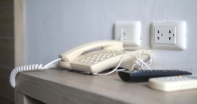 Close up of landline telephone and wall power outlet in hotel room