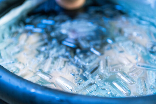 Young adult enjoying a cold plunge session surrounded by ice cubes to promote recovery, reduce muscle soreness, and enhance resilience. Ideal for wellness, fitness, recovery, and self-care concepts.