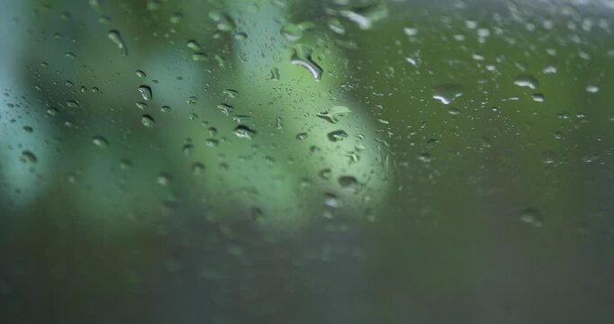 Close up of raindrops on glass with blurry green nature background