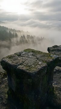 Mossy rock pillar overlooking foggy coniferous forest