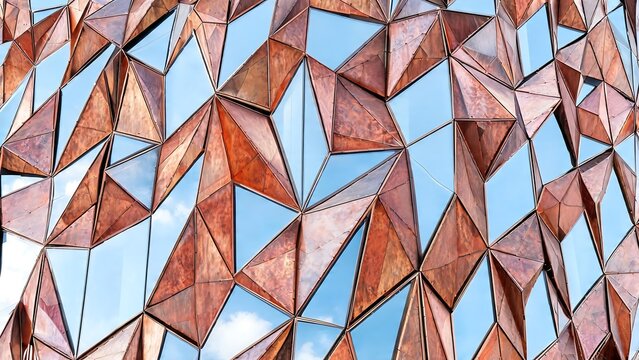 Modern Geometric Architecture with Faceted Copper Panels and Reflective Glass Facade under Blue Sky