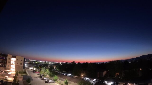 Time lapse of July 4th fireworks exploding in the distance over a dark city skyline.