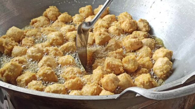 Fresh tofu being fried in hot oil during the preparation of crispy tahu kremes, showcasing the cooking process, golden texture, and traditional Indonesian culinary craftsmanship.