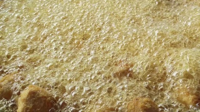 Fresh tofu being fried in hot oil during the preparation of crispy tahu kremes, showcasing the cooking process, golden texture, and traditional Indonesian culinary craftsmanship.