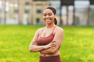 Smiling Black Woman With Crossed Arms Standing Outdoors In Athletic Wear, Displaying Confidence And Positivity At Park, Engaged In Fitness. Empowering Weight Loss Concept. © Prostock-studio