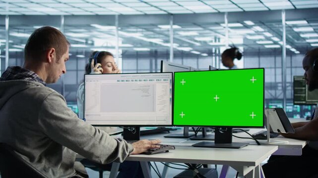 IT expert supervises data center supercomputers using a mockup monitor from an alternate angle, combining replaceable screen space with system oversight.