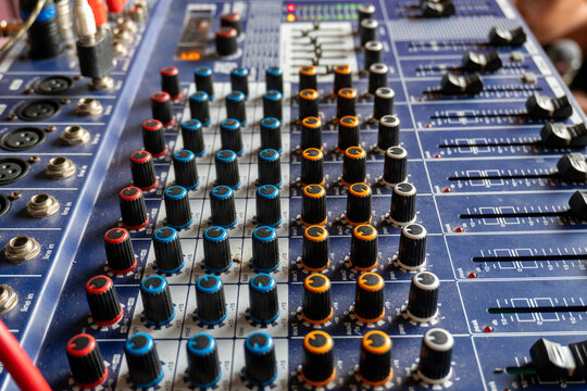 Close up of an analog audio mixing console with colorful knobs