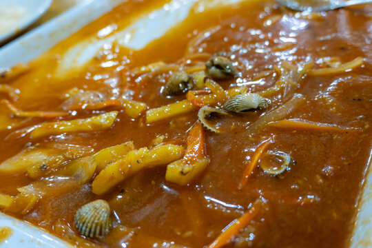 Empty plate with leftover spicy sauce and clam shells after a meal