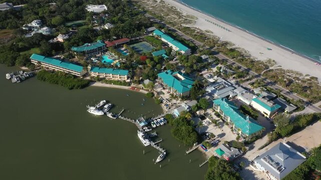 High-altitude aerial of Tween Waters Inn and Marina in Captiva, Florida, capturing pools, tennis courts, docked yachts, and the pristine white sand of the Gulf beach.