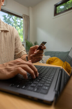 Focused person hand holding credit card typing laptop keyboard for online shopping from home. Making digital payment purchase transaction on internet using technology computer sitting at desk