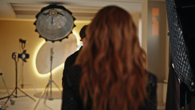 Photographer shooting redhead model studio. Cameraman directing fashion session.