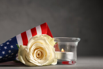 Obraz premium White rose, american flag, and lit candle for memorial day or veterans day remembrance