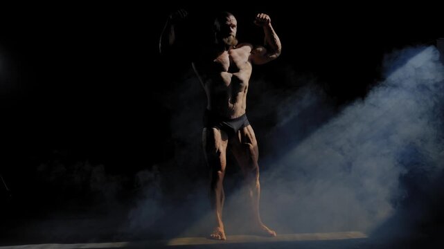 A male bodybuilder poses in shorts, showing off his muscles. 
