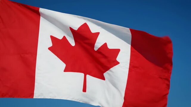 Canadian flag waving against blue sky