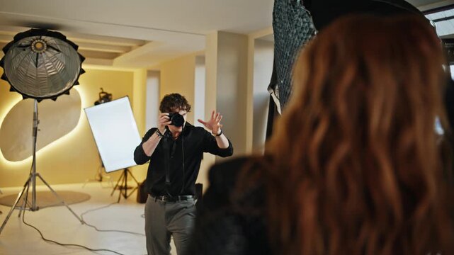 Fashion photoshoot studio backstage. Photographer holding camera taking