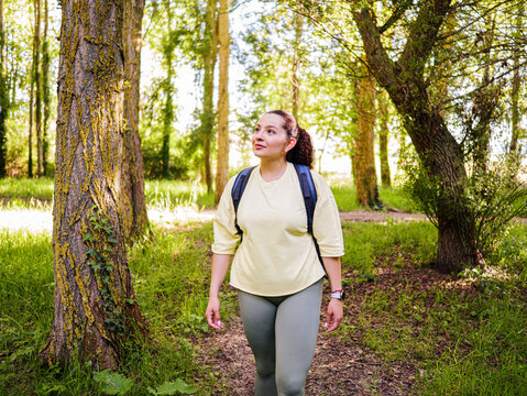Beautiful woman enjoy nature walking throught a forest making trekking 	
