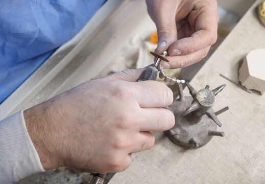 Dental prosthesis polishing with abrasive disc in closeup, skilled hands shaping custom bridgework for restorative dentistry, oral rehabilitation and laboratory manufacturing.