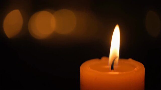 Single Candle Flame on Dark Background with Warm Bokeh and Copy Space