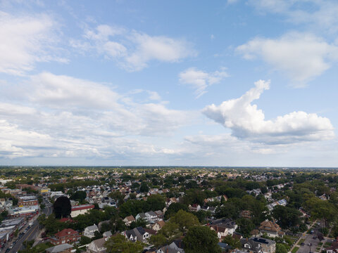 Aerial drone view of distant city skyline beyond a wooded suburban landscape in Hollis, Queens, New York City, New York