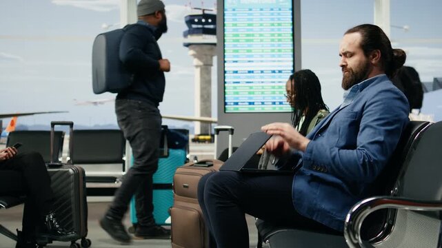 Businessman with a headache rubs his temples in an airport lounge during a work trip, showing exhaustion, stress, fatigue and workload pressure while waiting near the gate before a flight.