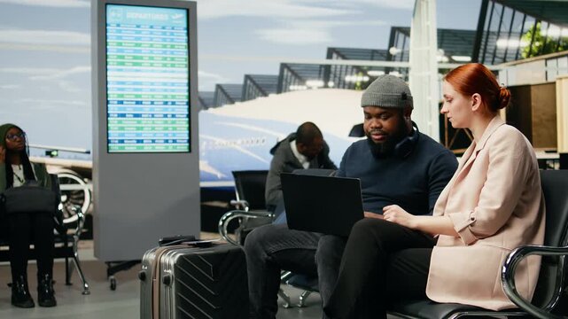 Diverse business colleagues prepare in an airport lounge for a meeting abroad, traveling as a delegation to a multinational company event and headquarters during a work trip before departure.