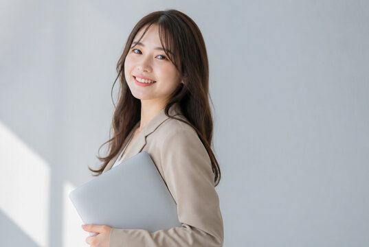 ノートパソコンを抱えて笑顔でカメラを見つめる女性 Generative AI