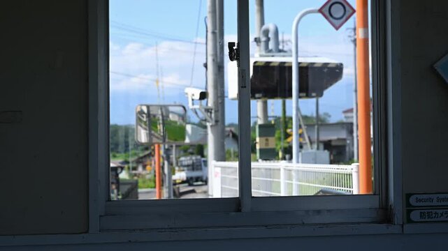 駅舎の窓越しに眺めるローカル線の踏切風景