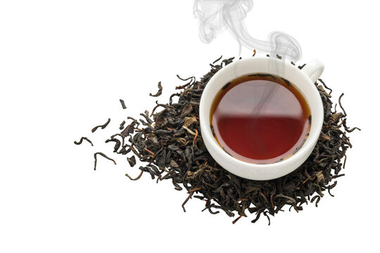 A white ceramic cup filled with hot steaming black tea placed on a pile of loose dried tea leaves against a solid plain black background surface