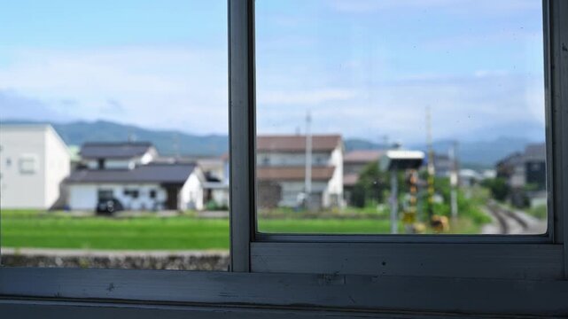 窓枠越しに眺める線路と踏切のある長閑な風景