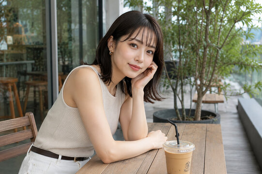 カフェテラスでアイスコーヒーを前に微笑む女性