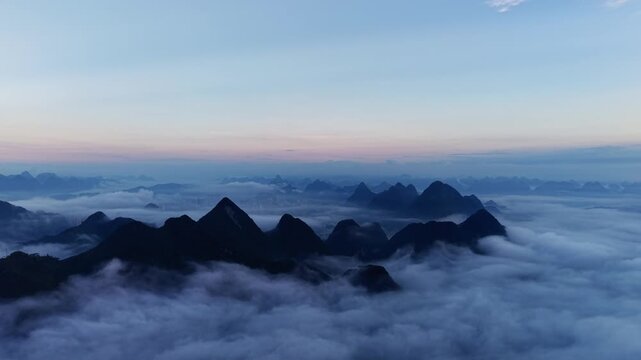 Cinematic aerial: Low-level stratus and morning cloud sea over karst county with river cutting through valley