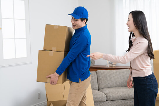 若い女性の引っ越しを請け負う若い業者　ライフスタイルイメージ