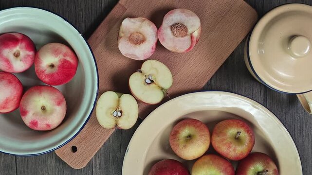 Red apple pink peach fruit whole sliced half seed tin plate chopping board wooded background