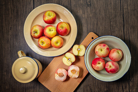 Red apple pink peach fruit whole sliced half seed tin plate chopping board wooded background