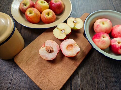 Red apple pink peach fruit whole sliced half seed tin plate chopping board wooded background