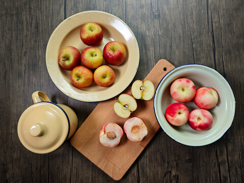 Red apple pink peach fruit whole sliced half seed tin plate chopping board wooded background