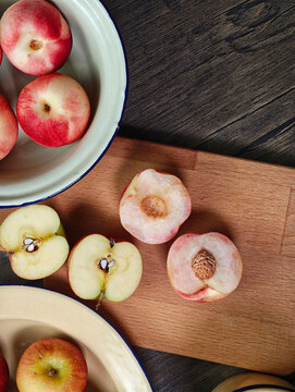 Red apple pink peach fruit whole sliced half seed tin plate chopping board wooded background