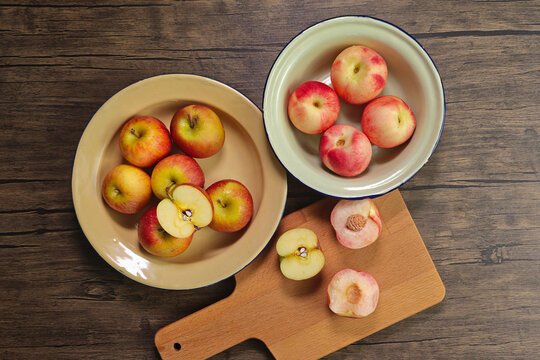 Red apple pink peach fruit whole sliced half seed tin plate chopping board wooded background